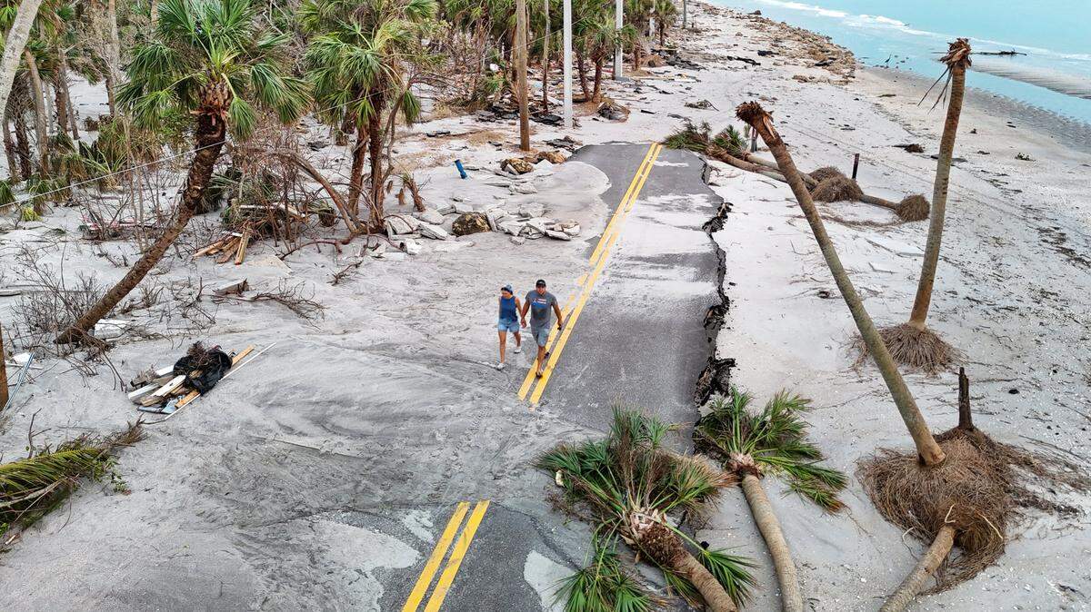 Anna and Alex Marchuk, left to right, walk along a washed out Manasota Key Road on Friday, October 11, 2024. The extensive damage was caused by hurricanes Helene and Milton in Manasota Key, Florida,