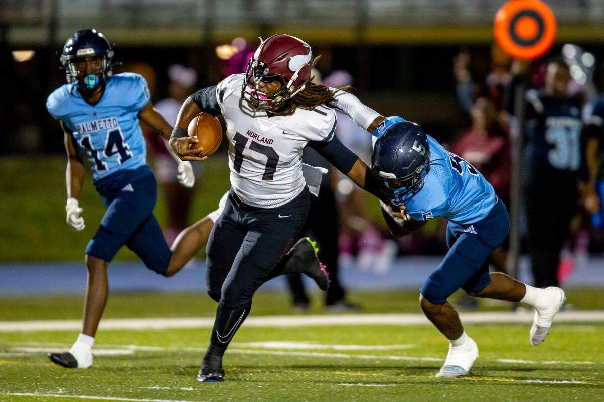 Miami Norland quarterback Ennio Yapoor (17) stiff-arms Miami Palmetto cornerback Omari Winkfield (5) before scoring during the first quarter of a high school football game at Tropical Park in Miami, Florida, on Thursday, October 20, 2022.
