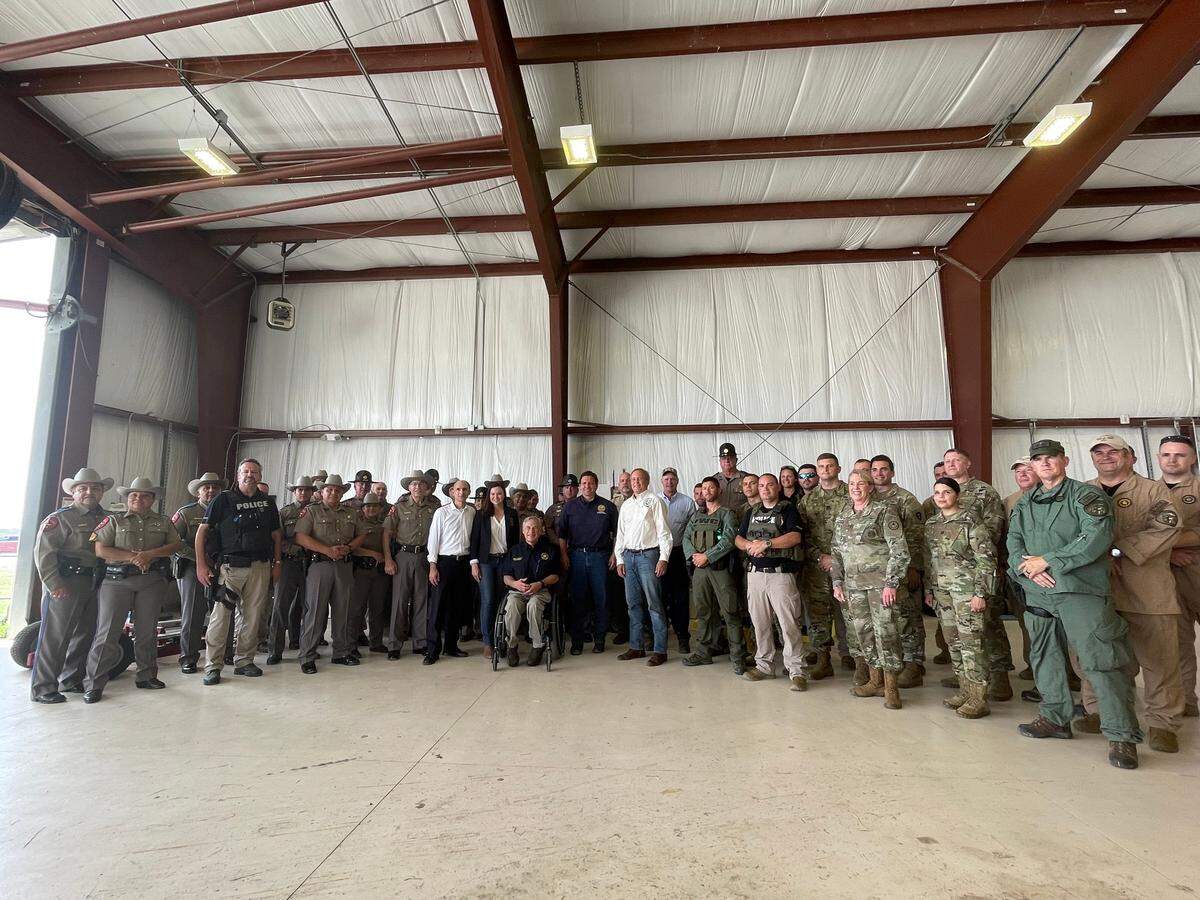 En esta foto tomada el sábado 17 de julio de 2021 en un hangar del aeropuerto de Del Río, Texas, la procuradora general de la Florida, Ashley Moody, está cerca del centro del grupo a la izquierda del gobernador de Texas, Greg Abbott, mientras que el gobernador Ron DeSantis está al otro lado de Abbott.