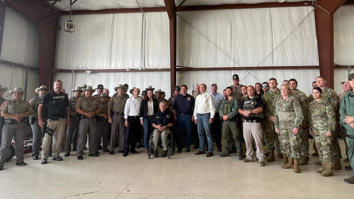 In this photo taken Saturday, July 17, in an airport hangar in Del Rio, Texas, Florida Attorney General Ashley Moody is near the center of the group to the left of Texas Gov. Greg Abbott while Gov. Ron DeSantis is on the other side of Abbott. Moody announced on Wednesday, July 21, that she had tested positive for COVID-19.