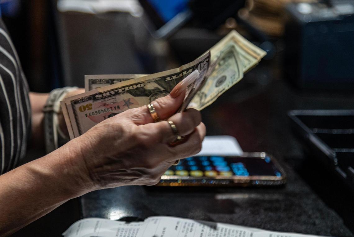 A waitress counts some money as she closes her shift at the Latin Cafe 2000 in Miami.
