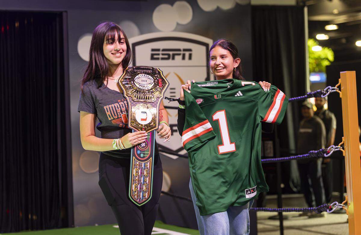 Luna Godoy, right, and Rebecca Castillo, hold props and strike poses for a video while visiting the Playoff Fan Central at the Miami Beach Convention Center on Friday, Jan. 16, 2025, in Miami Beach, Fla. Fans can visit the event ahead of the College Football Playoff National Championship Game between the Miami Hurricanes and the Indiana Hoosiers and enjoy a variety of family-friendly interactive experiences.
