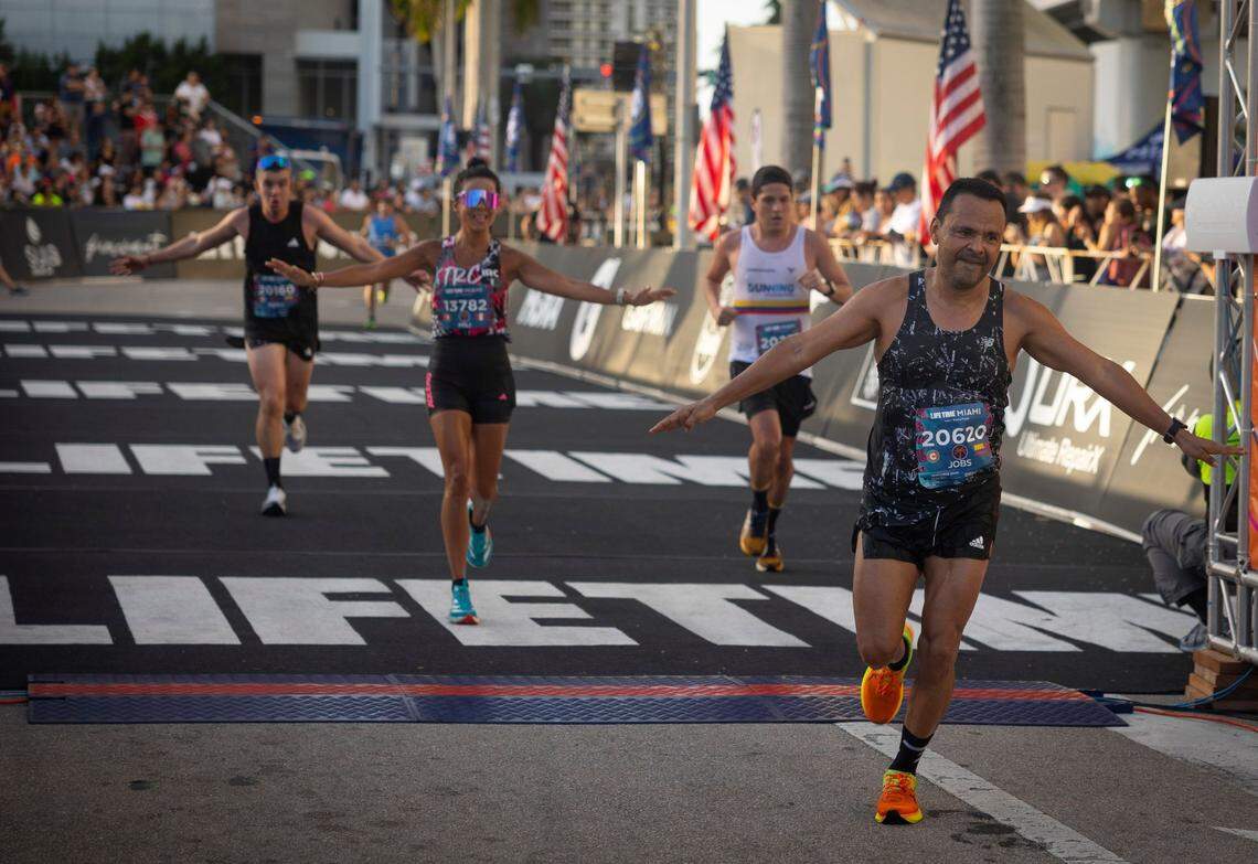 Jose Omas Botero, right, crosses the finish line of the half during the Life Time Miami Marathon and Half on Sunday, Jan. 28, 2024, finishing at Bayfront Park in downtown Miami.
