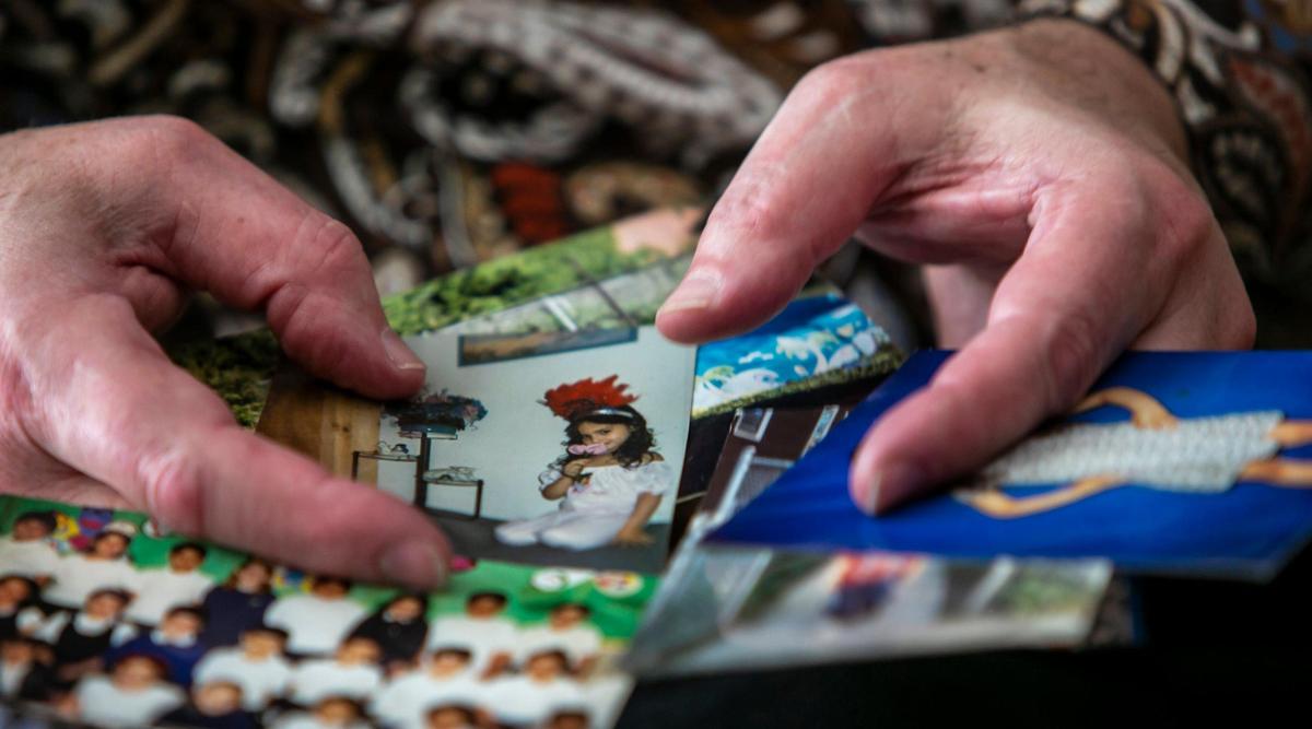 Heriberto Delvalle holds pictures of his daughter when she was a child. She now lives in Chicago and is trying to help him move closer to her.