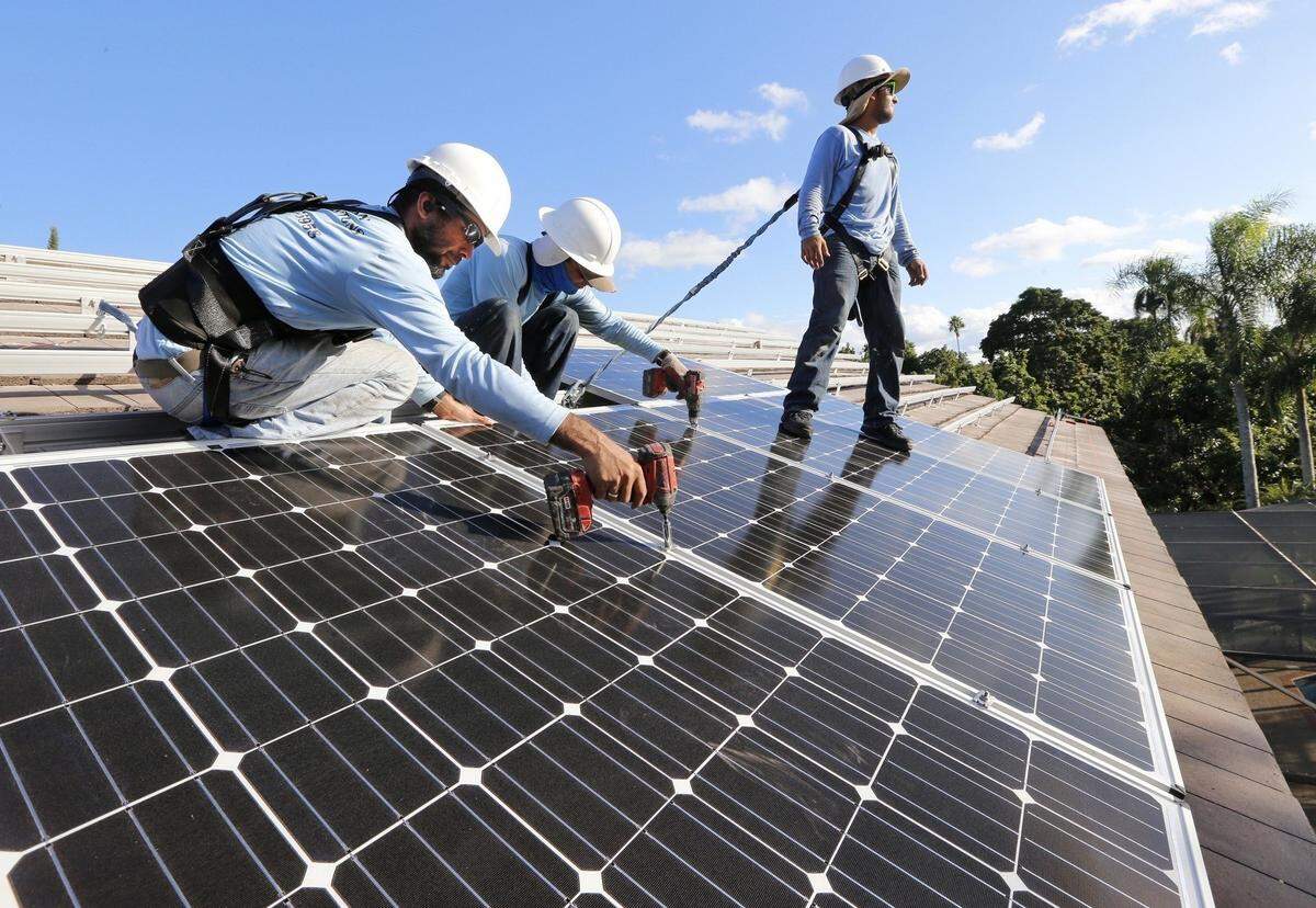 Workers install solar panels at a home in South Dade.