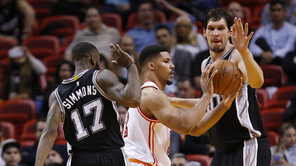 Miami Heat forward Jarnell Stokes, center, passes past San Antonio Spurs guard Jonathon Simmons (17) and center Boban Marjanovic during the second half of an NBA basketball game, Tuesday, Feb. 9, 2016, in Miami. The Spurs defeated the Heat 119-101.