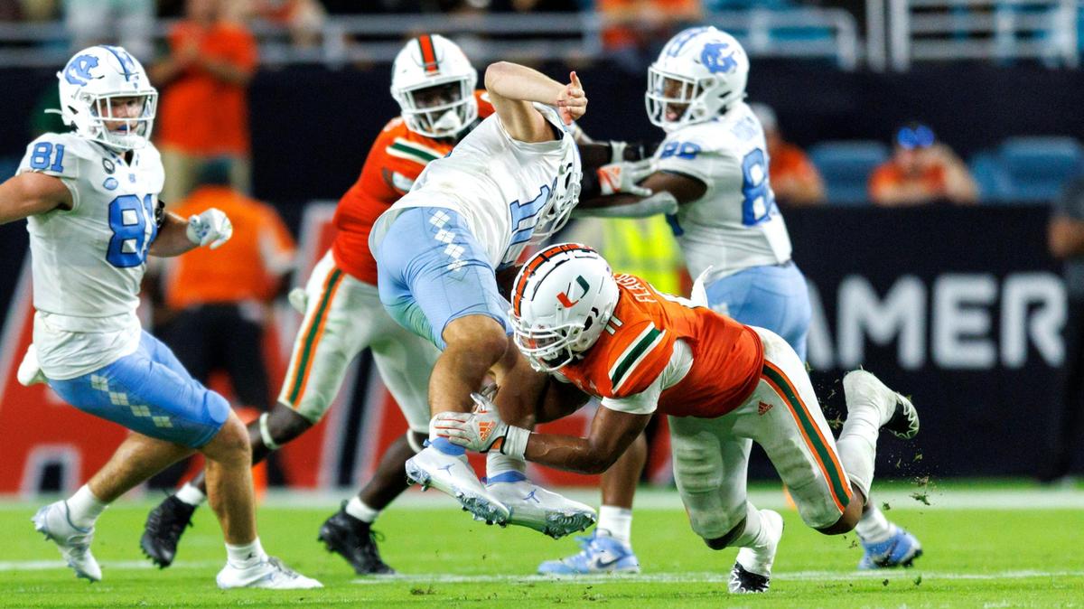 North Carolina Tar Heels quarterback Drake Maye (10) is tackled by Miami Hurricanes linebacker Corey Flagg Jr. (11) during the fourth quarter of an ACC conference football game at Hard Rock Stadium on Saturday, October 8, 2022 in Miami Gardens, Florida..