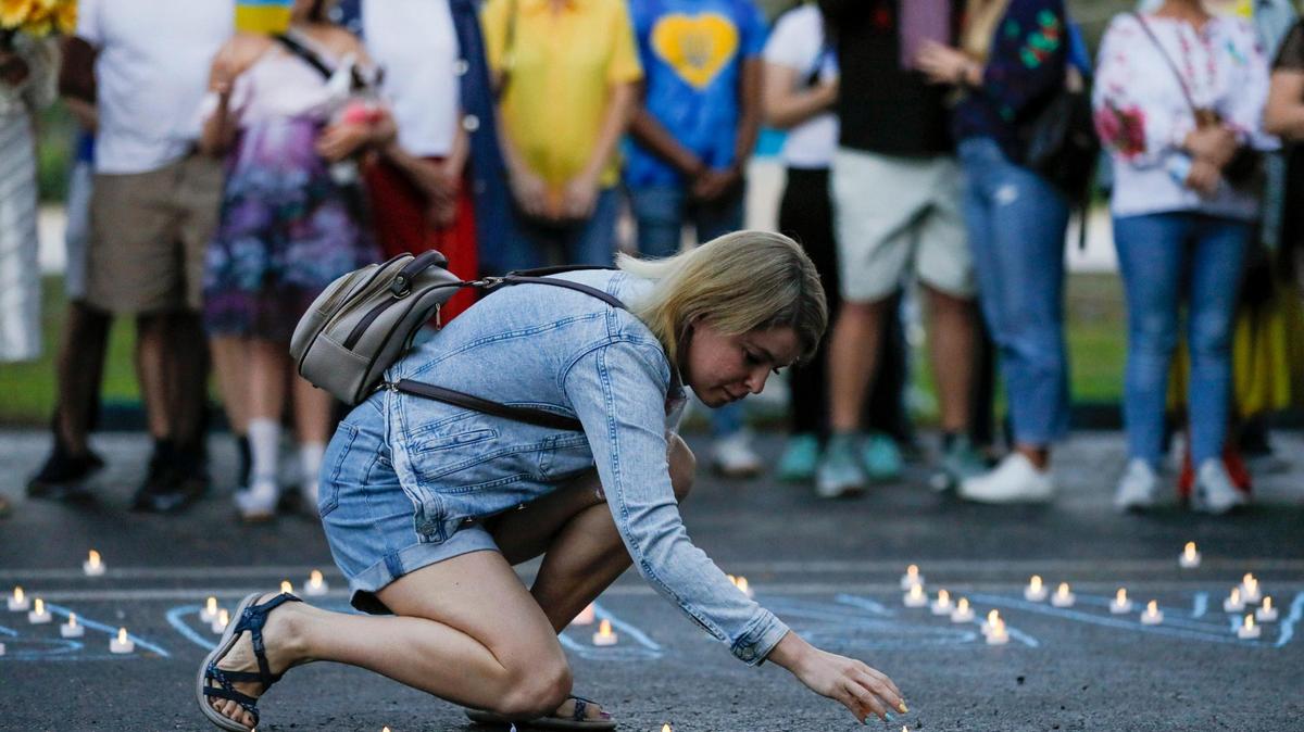 Una mujer coloca velas artificiales en el suelo durante una manifestación y vigilia en apoyo de los ucranianos afectados por la invasión rusa de Ucrania en la iglesia ortodoxa ucraniana de San Nicolás en 5031 SW 100th Ave., en Cooper City, Florida, el sábado 26 de marzo de 2022. .