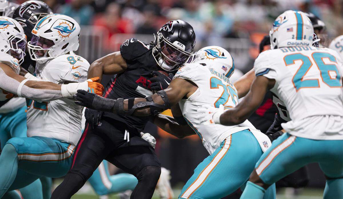 Miami Dolphins linebacker Jordyn Brooks (20) tackles Atlanta Falcons running back Bijan Robinson (7) in the first half of their NFL game at Mercedes-Benz Stadium on Sunday, Oct. 26, 2025, in Atlanta, Ga.