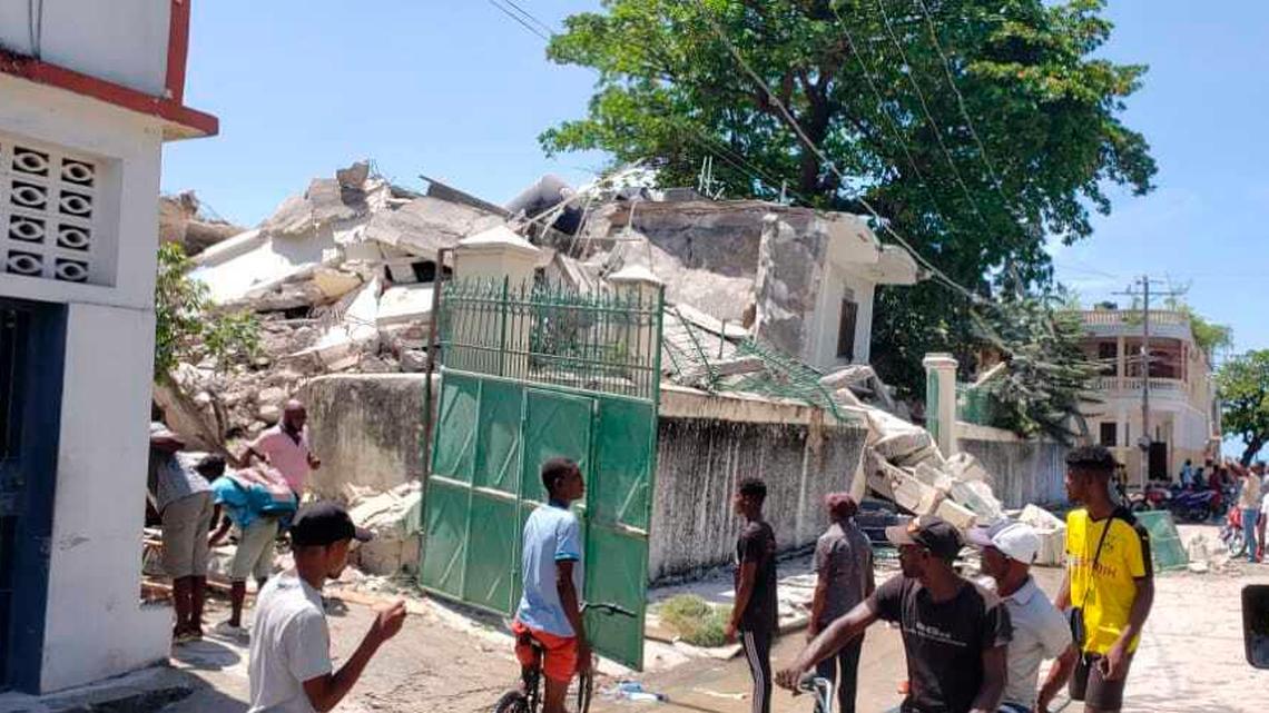People stand outside the residence of the Catholic bishop after it was damaged by an earthquake in Les Cayes, Haiti, Saturday, Aug. 14, 2021.