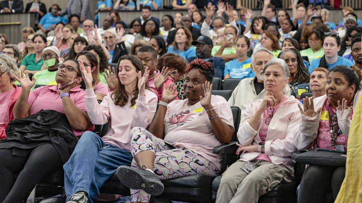 Audience members at the first Miami-Dade County budget hearing silently cheer comments in the packed chambers, where applause is banned. The hearing began Thursday, Sept. 4, 2025 but stretched well into the morning of Sept. 5 at the Stephen P. Clark Government Center in Miami. 