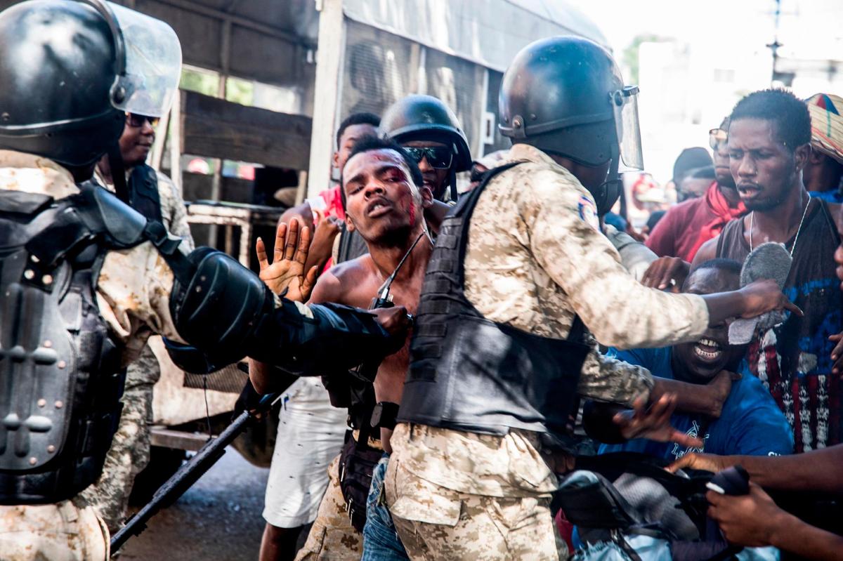 An alleged phone thief who was beaten by the protesters is arrested by the police during a demonstration demanding the resignation of President Jovenel Moise in the Haitian capital in Port-au-Prince on October 28, 2019.