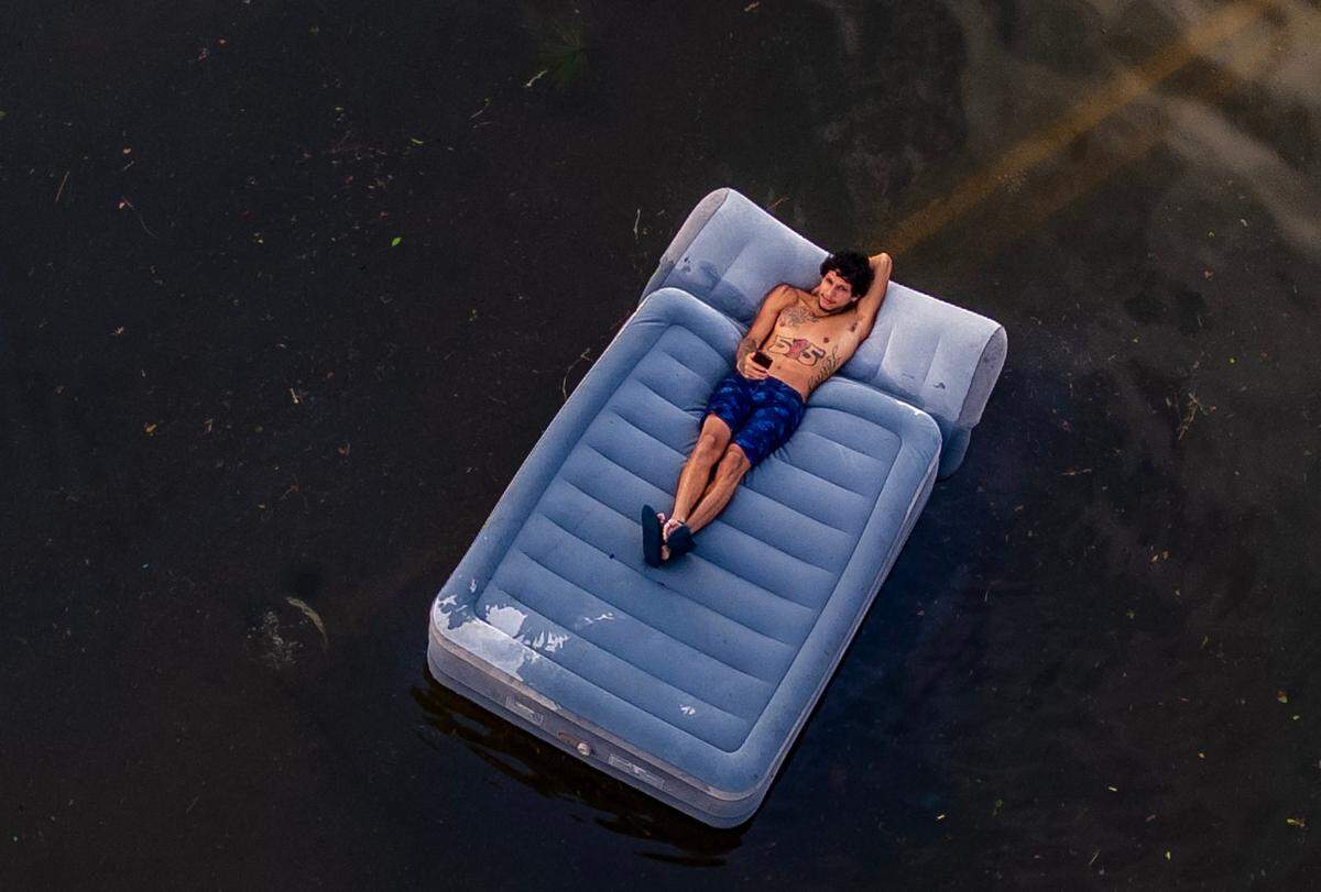 A man lies on an inflatable mattress floating on a flooded street in North Tampa, on Thursday, October 10, 2024, a day after Hurricane Milton crossed Florida’s Gulf Coast.