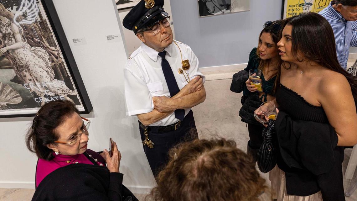 Guests look on in disbelief at a sculpture titled ‘Security Guard’ by Marc Sijan on display during Art Miami at One Herald Plaza on Tuesday, Dec. 3, 2024, in Miami, Fla.