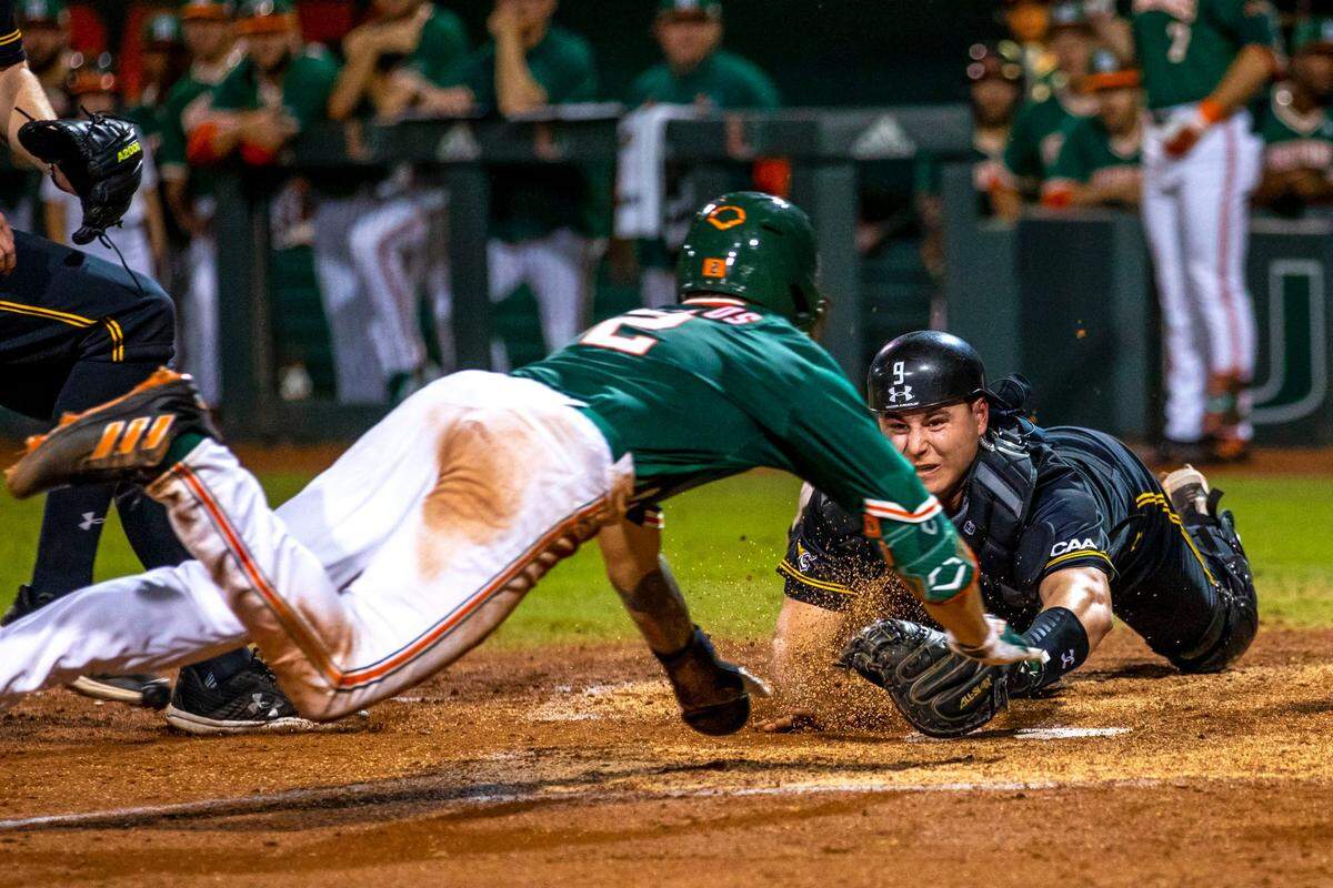 Towson University catcher Burke Camper (9) tags out University of Miami base runner CJ Kayfus (2) during the second inning of an NCAA baseball game inside Alex Rodriguez Park at Mark Light Field in Coral Gables, Florida, on Friday, February 18, 2022.