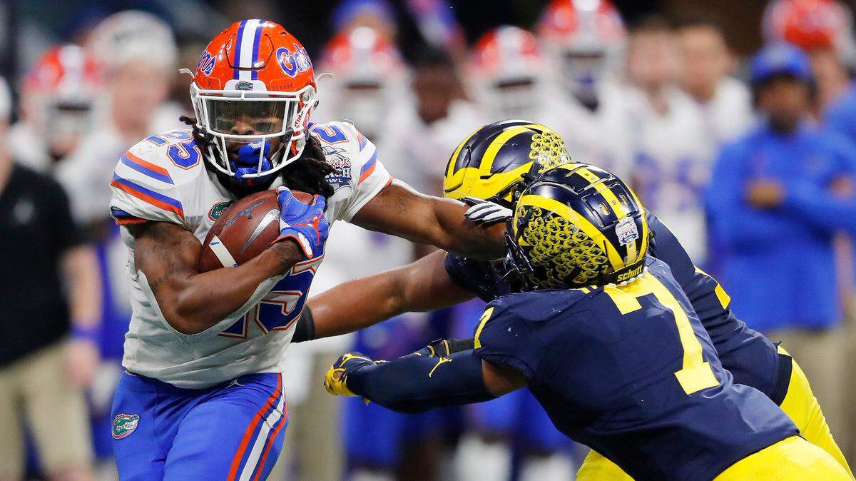 Florida running back Jordan Scarlett (25) runs by Michigan linebacker Khaleke Hudson (7) during the first half of the Peach Bowl NCAA college football game, Saturday, Dec. 29, 2018, in Atlanta.