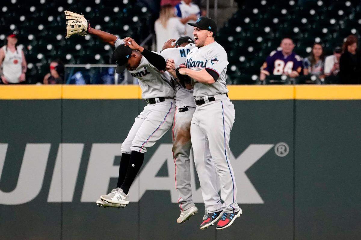 Miami Marlins outfielders from left; Corey Dickerson (23), Starling Marte (6), and Adam Duvall (14) celebrate after defeating the Atlanta Braves in a baseball game Monday, April 12, 2021, in Atlanta.