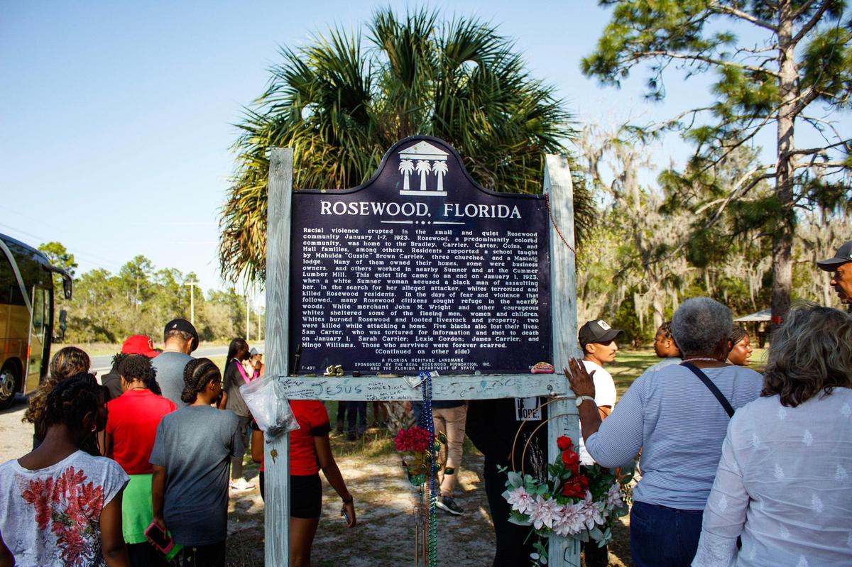 Visitors interact with the historical marker explaining the Rosewood Massacre in Rosewood, Florida, on Sunday, March 5, 2023. The 1923 massacre left eight people dead — six Black, two white — and an entire community razed after a white woman falsely accused a Black man of beating her.