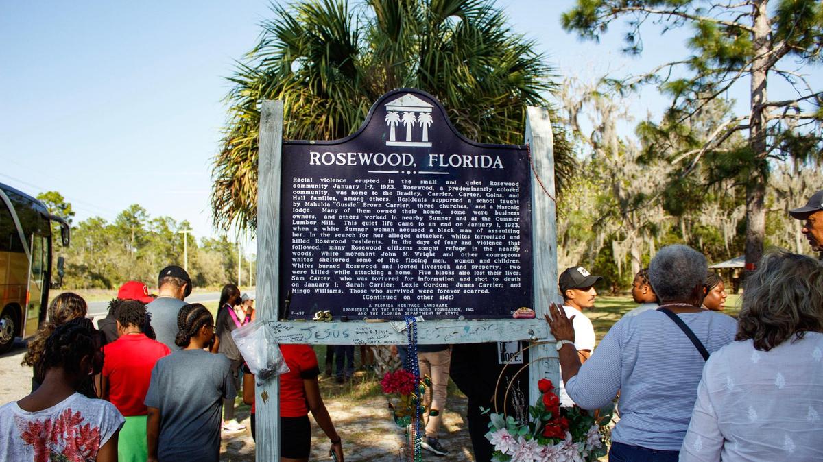 Visitors interact with the historical marker explaining the Rosewood Massacre in Rosewood, Florida, on Sunday, March 5, 2023. The 1923 massacre left eight people dead — six Black, two white — and an entire community razed after a white woman falsely accused a Black man of beating her.