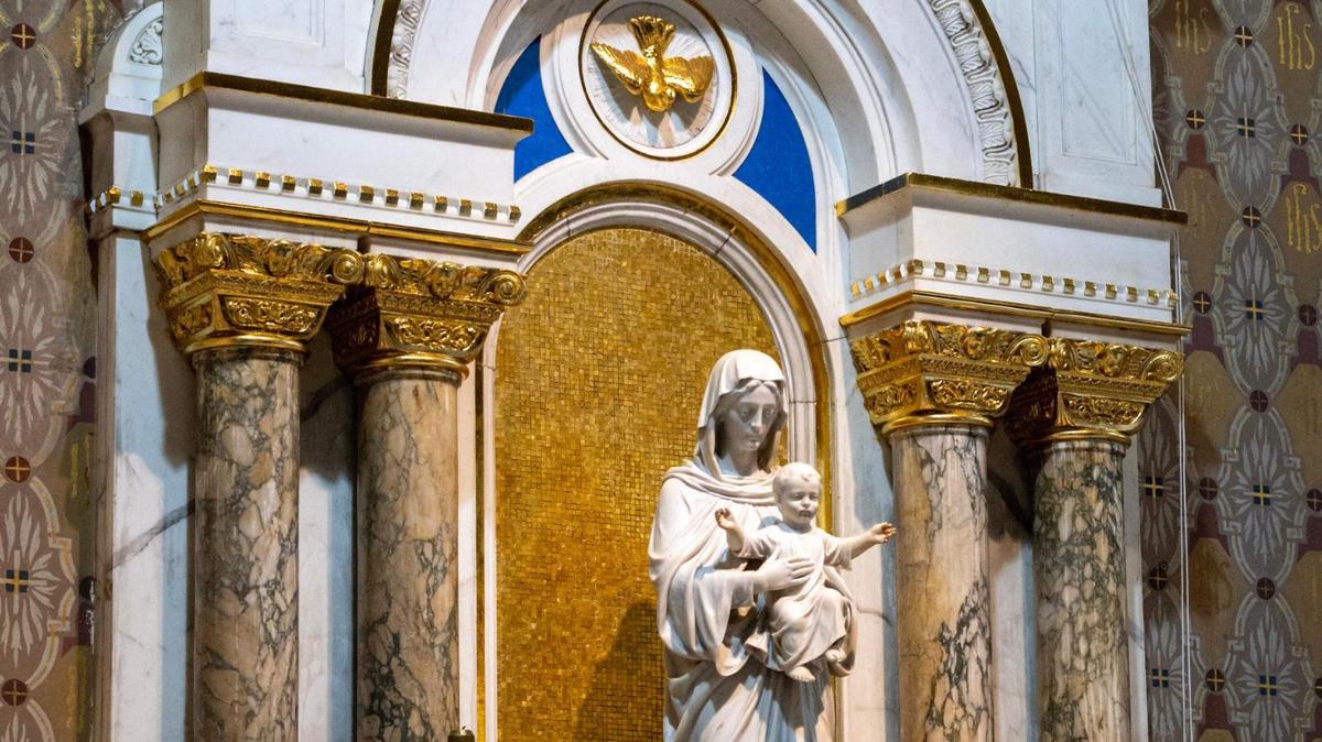 A statue of the Virgin Mary holding a baby Jesus Christ stands inside the sanctuary at The Gesu Church in Downtown Miami, Florida.