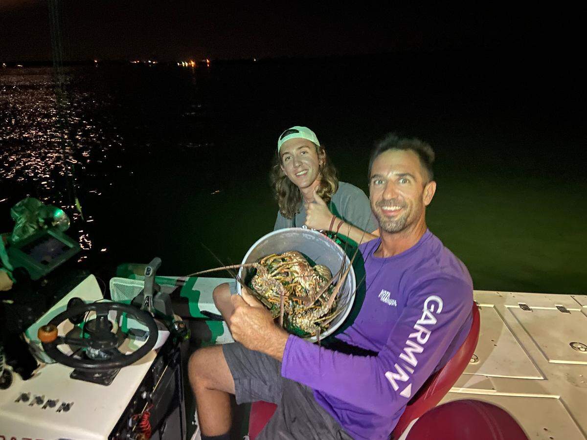 Steve Jahn holds a bucket full of spiny lobster while he sits next to his son Reece on their boat Wednesday, July 28, 2021, off the Upper Florida Keys.