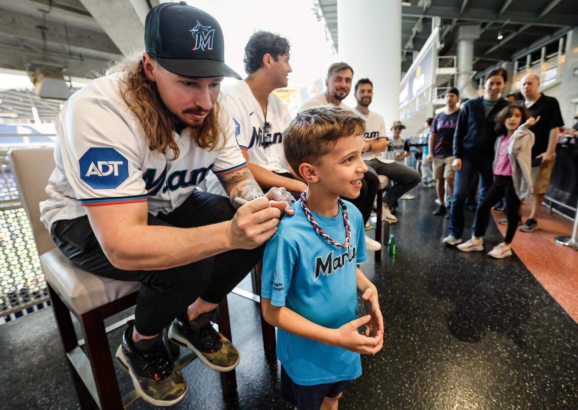 Miami Marlins pitcher Lake Bachar signs Lucas Sanchez's t-shirt during Marlins Fan Fest at loanDepot park.