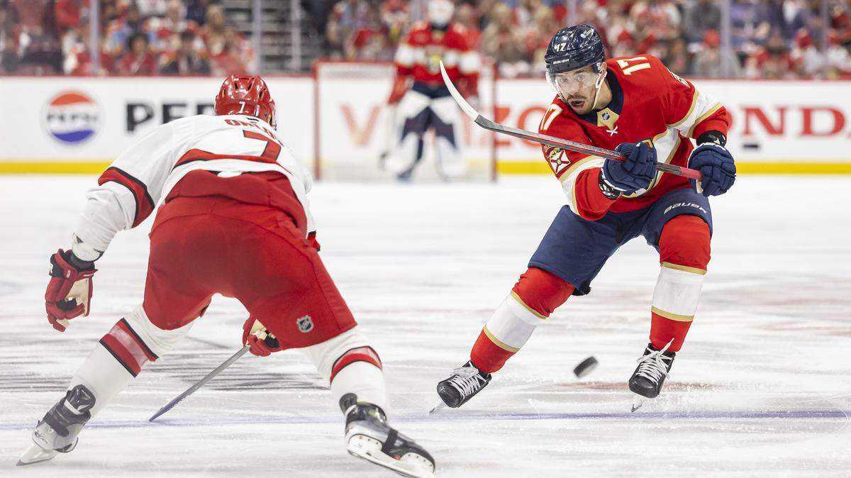 Florida Panthers center Evan Rodrigues (17) shoots the puck as Carolina Hurricanes defenseman Dmitry Orlov (7) defends in the second period of Game 3 during the Eastern Conference final of the NHL Stanley Cup playoffs at Amerant Bank Arena on Saturday, May 24, 2025, in Sunrise, Fla.