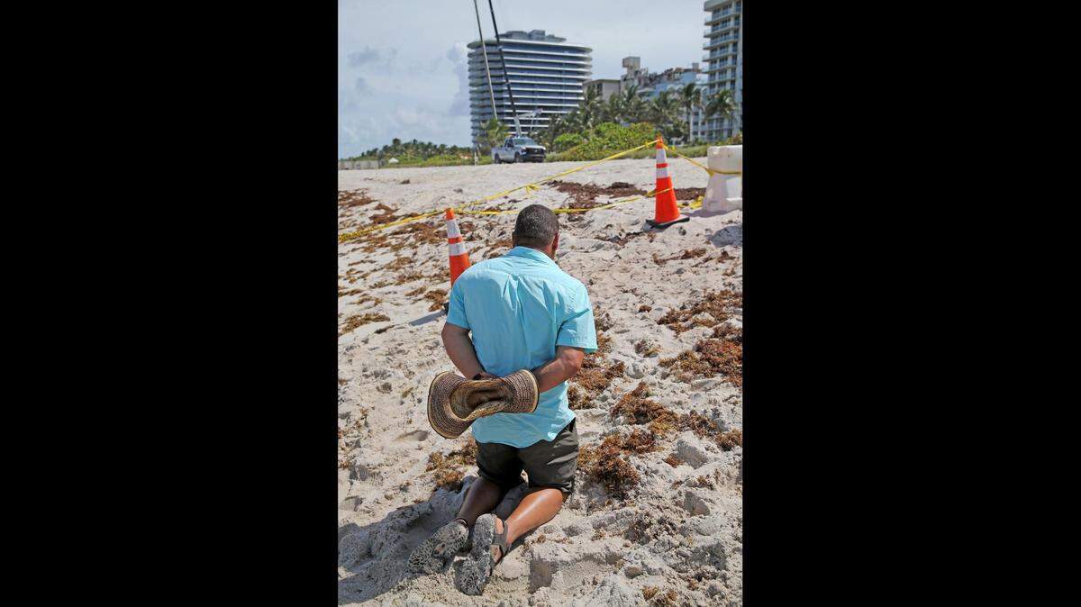 Un hombre reza en el lugar del derrumbe del edificio de condominios Champlain Towers South en Surfside, Florida, el 25 de junio de 2021. El edificio se derrumbó la madrugada del jueves.