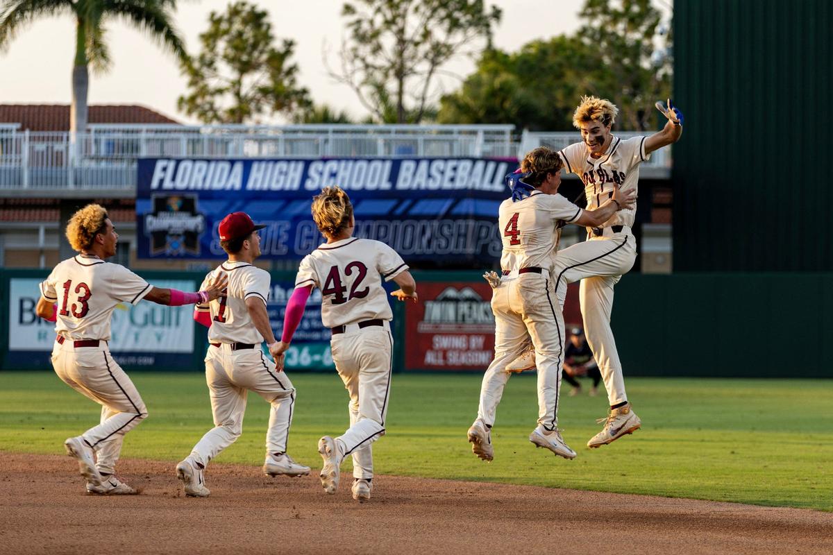 Marjory Stoneman Douglas players swarm around Nick Diaz (11) after he hit a walk-off single to defeat Windermere 3-2 in extra innings for the Class 7A state baseball championship game at Hammond Stadium on Saturday, May 18, 2024, in Fort Myers, Fla.