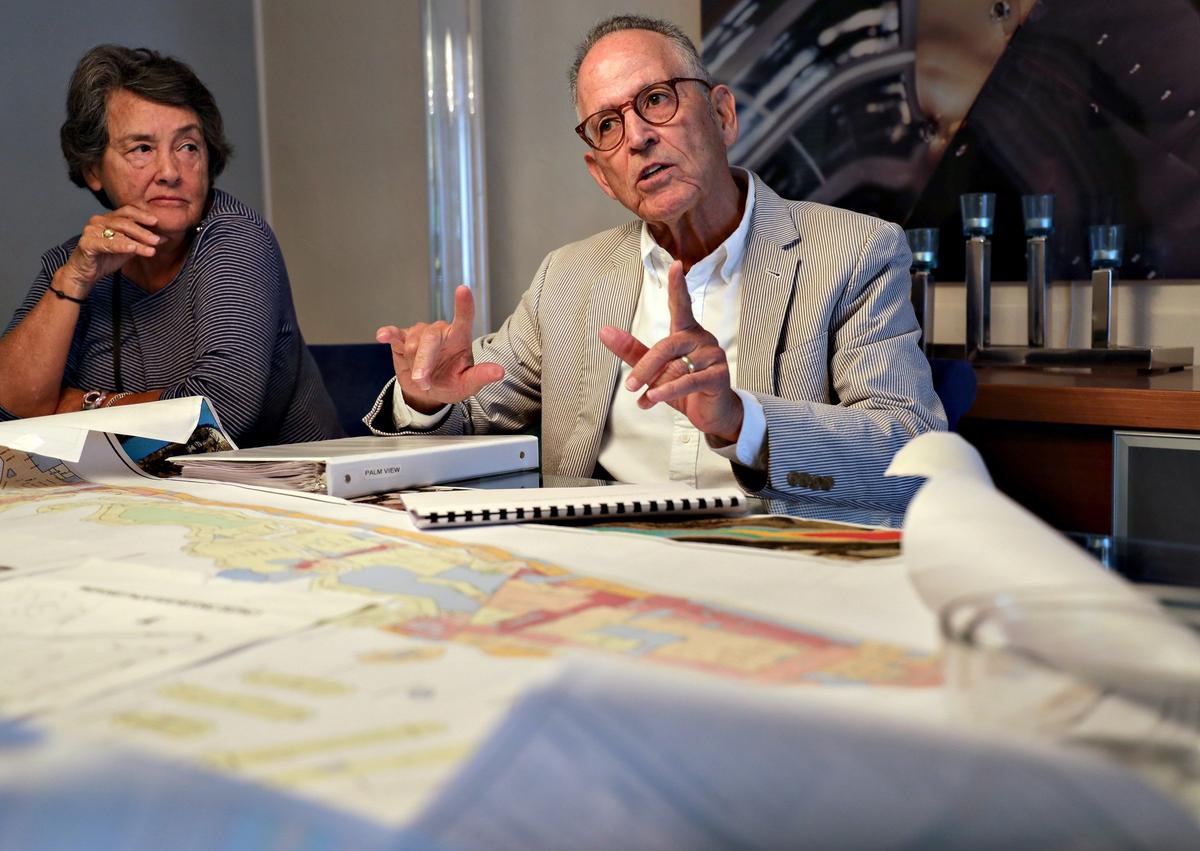 Palm View resident Jay Levy, right, explains his opposition to the historic designation of the Palm View neighborhood as fellow resident Luz Latorre listens.