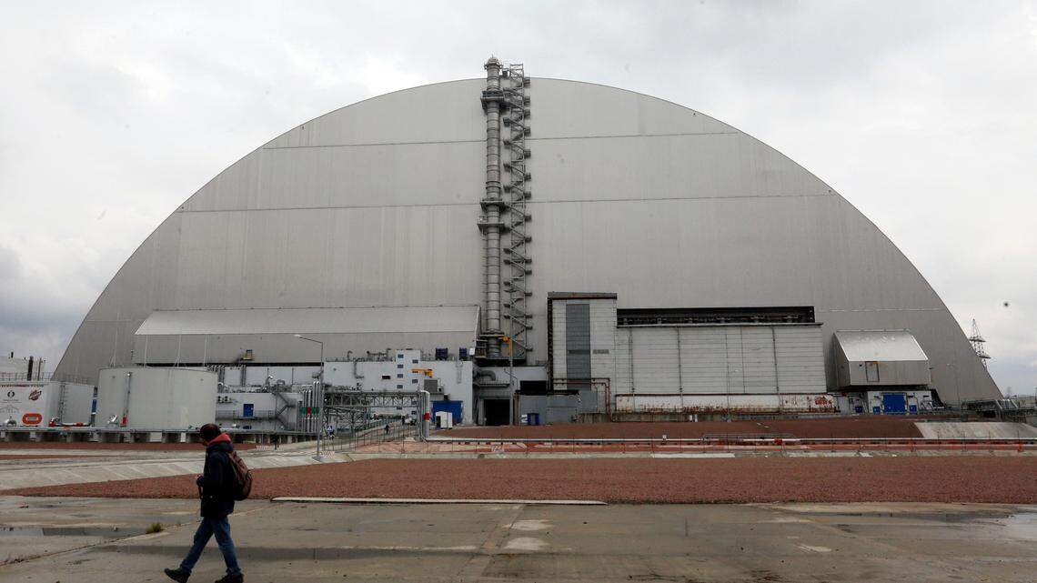 A man walks past a shelter covering the exploded reactor at the Chernobyl nuclear plant, in Chernobyl, Ukraine, in 2021. Russian forces have seized control of the facility.
