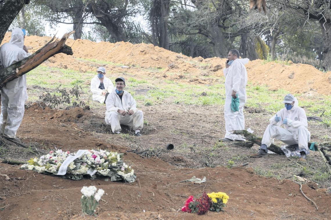 Workers rest as they wait for more COVID-19 victims to bury at the Sao Luiz cemetery in Sao Paulo, Brazil, on Thursday.