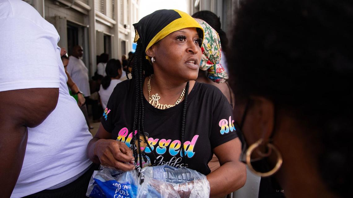 Nicole Cannon passes water bottles out to people waiting to sign up for LIHEAP, a light bill assistance program, at Annie L. Weaver Health Center in Pompano Beach, Fla., on Thursday, July 20, 2023. “I’m trying to get everybody out of here,” said Cannon, who had been waiting for over two hours for assistance.
