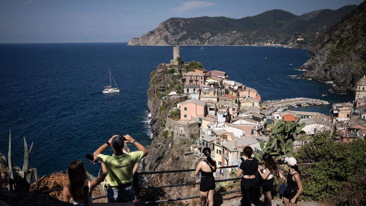 Tourists look out from a hillside in Vernazza on August 14, 2024 in the Cinque Terre National Park, near La Spezia, Nortwestern Italy.