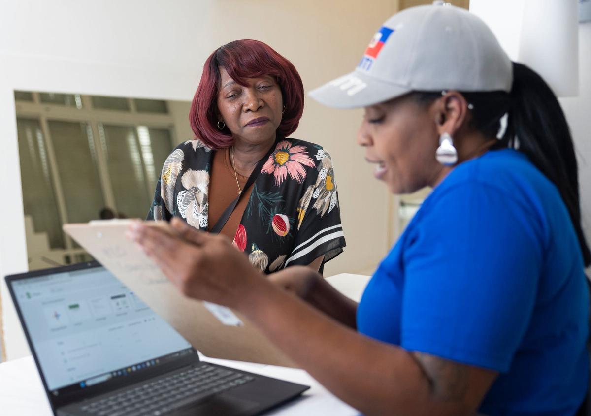 Enise Joseph, left, is registered for a community resource fair by Claudya Gebara, a volunteer at Jobs For Us, at the Magic City Innovation District on Friday, May 31, 2024, in Miami, Fla. The fair aimed at helping recently arrived Haitians and other immigrants connect with health care providers and prospective employers.