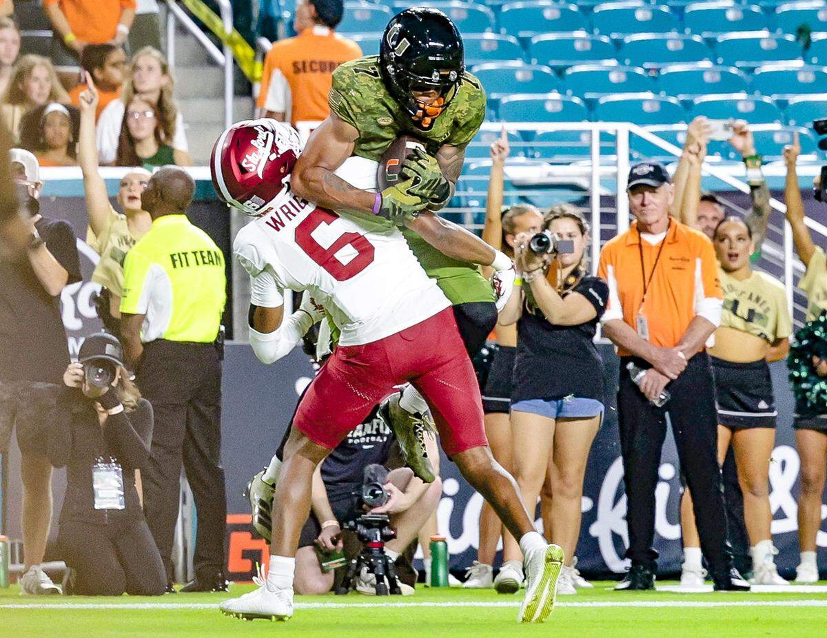 Miami Hurricanes wide receiver CJ Daniels (7) scores as Stanford Cardinal cornerback Collin Wright (6) defends in the first half of their NCAA football game at Hard Rock Stadium in Miami Gardens, Florida, on Saturday, October 25, 2025.
