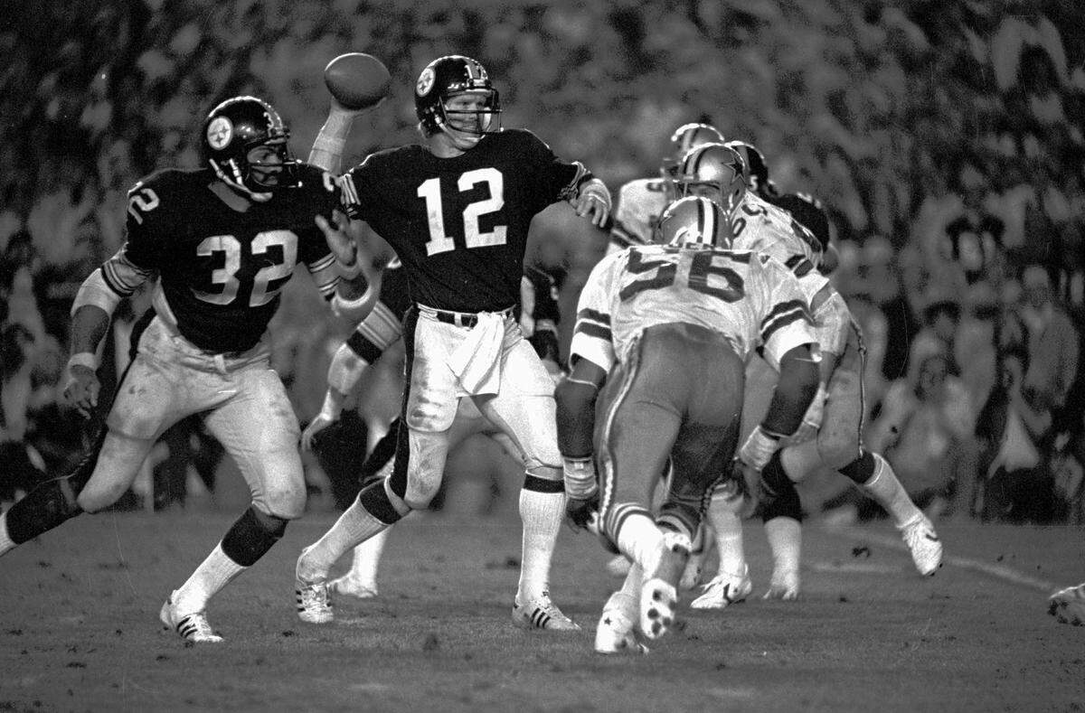 Pittsburgh Steelers quarterback Terry Bradshaw winds up to fire a pass during Super Bowl XIII against the Dallas Cowboys in Miami Jan. 21, 1979. Bradshaw fired four touchdown passes and shattered two Super Bowl passing records in leading the Steelers to a 35-31 win over the Cowboys. At left, is Steelers Franco Harris and at right Cowboys Thomas Henderson (56).