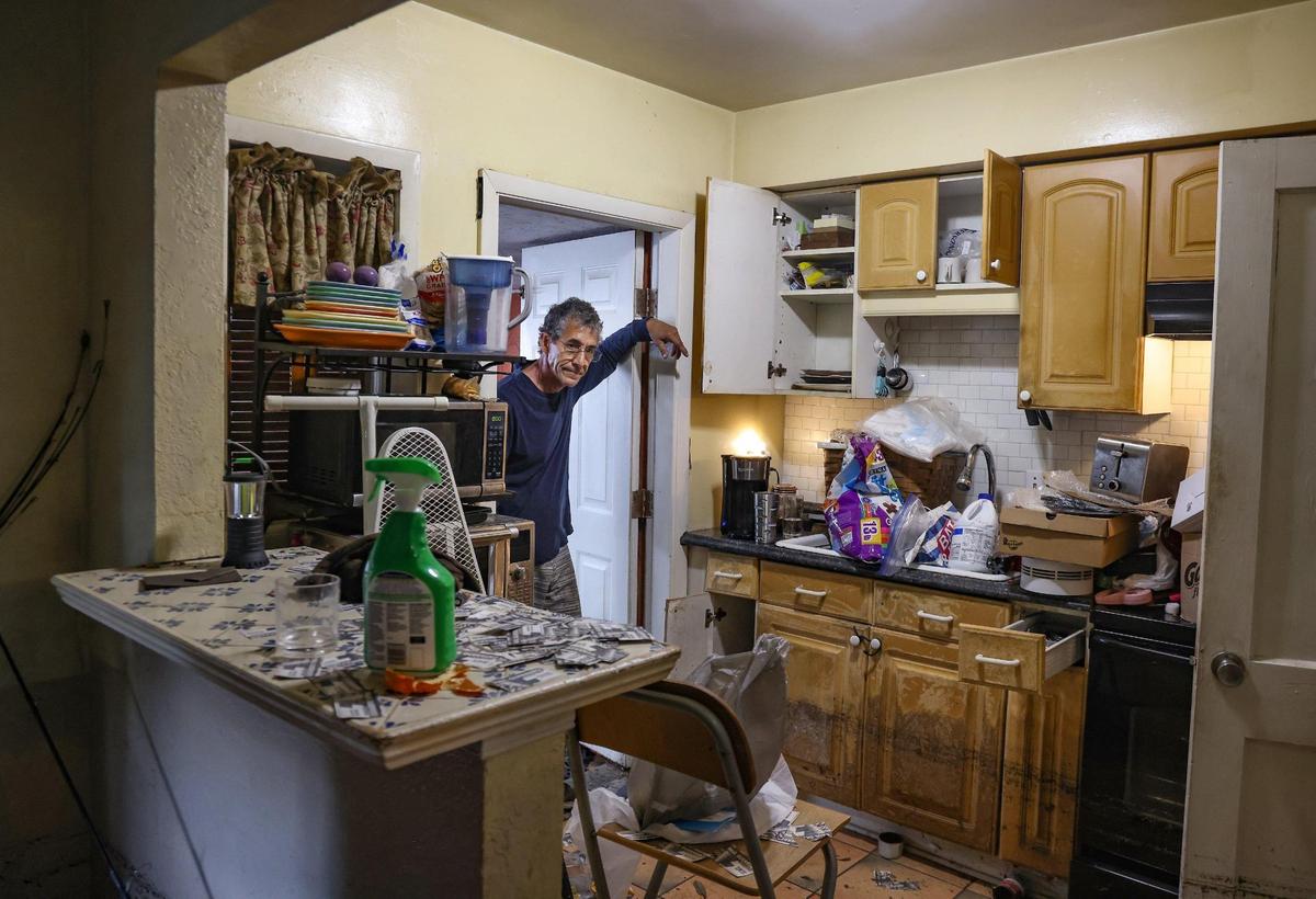 Paul Guerrero pauses to assess the damage while a restoration company surveys his home.