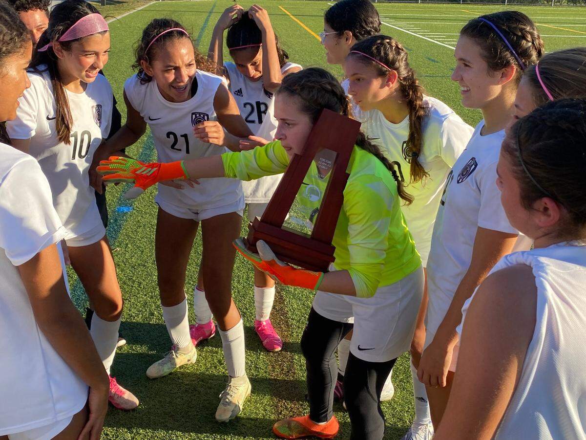 True North Classical Academy’s girls’ soccer goalkeper Gabriela Scott playfully mimics talking on a phone with the regional championship trophy while her players listen and later celebrate. The Titans clinched their first ever trip to the state semifinals following a 4-2 win over South Florida HEAT in the Region 4-2A final at Tequesta Trace Park in Weston, Fla.