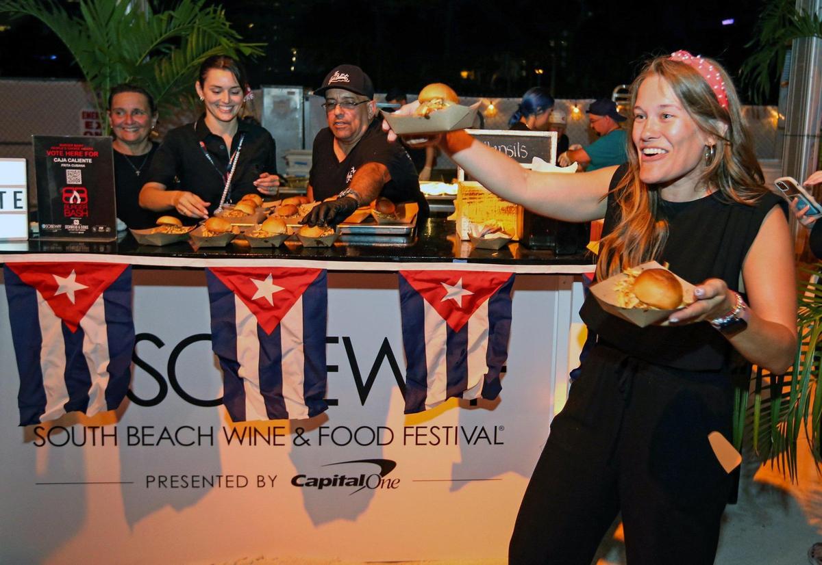 Lizbeth Villamarin offers up Frita Cubana at the Caja Caliente both during the Burger Bash at the South Beach Wine & Food Festival on the sand by the Ritz Carlton in Miami Beach, Florida on Thursday, February 23, 2023.
