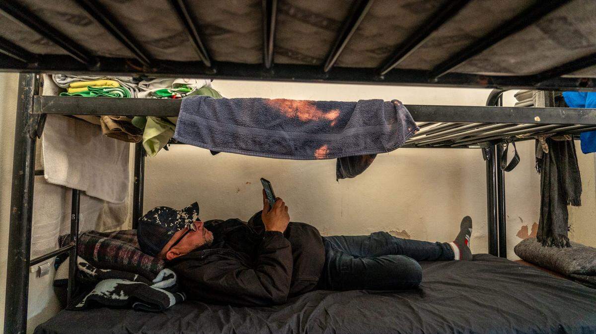 Yorjel Navarro, 42, of Cuba, messages family and friends as he lies on a bed at the Casa del Migrante la Divina Providencia, a migrant shelter in San Luis Rio Colorado, Sonora, Mexico, on Feb. 2, 2023.