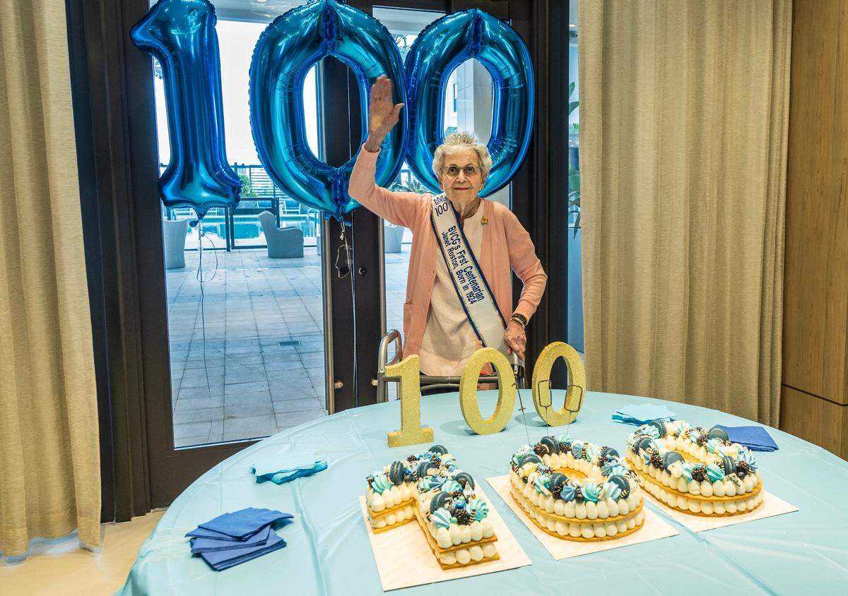 Janet Roston posed for pictures in front of the cake to celebrate her 100th birthday at the Belmont Village community center in Coral Gables. She worked with Knight-Ridder, the former owner of the Miami Herald, and attributes her longevity to staying active both physically and mentally. on Friday September 27, 2024.