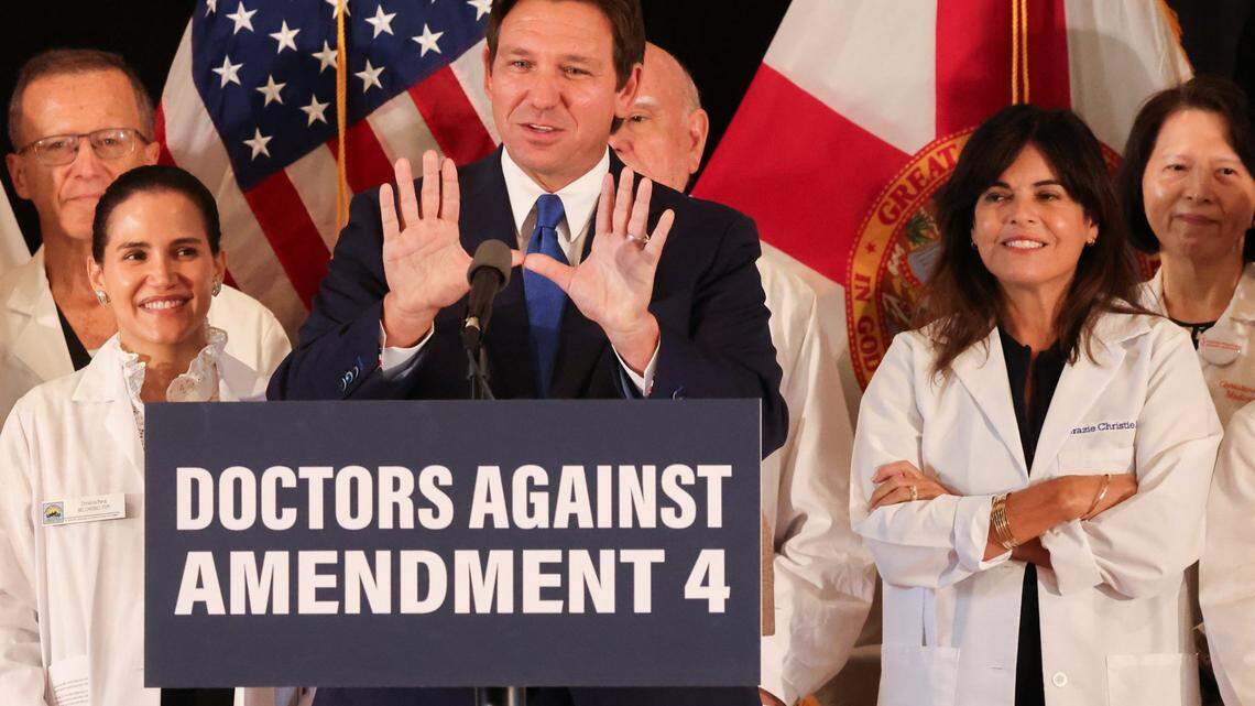 Florida Governor Ron DeSantis acknowledges the undefeated UM Hurricane football team as comments on his opposition to Amendment 4 while several doctors stand behind him during his press conference at Comber Hall on Monday, October 21, 2024, the first day of early voting in Coral Gables, Florida.