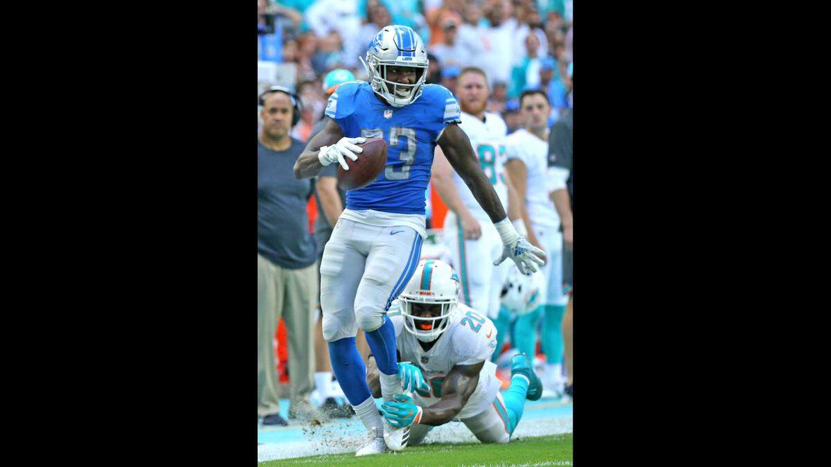 Miami Dolphins Reshad Jones reaches for Detroit Lions Kerryon Johnson in the second quarter as he advances the ball to help with the Lons first touchdown at Hard Rock Stadium in Miami Gardens, Florida, October 21, 2018. Sunday, October, 21, 2018
