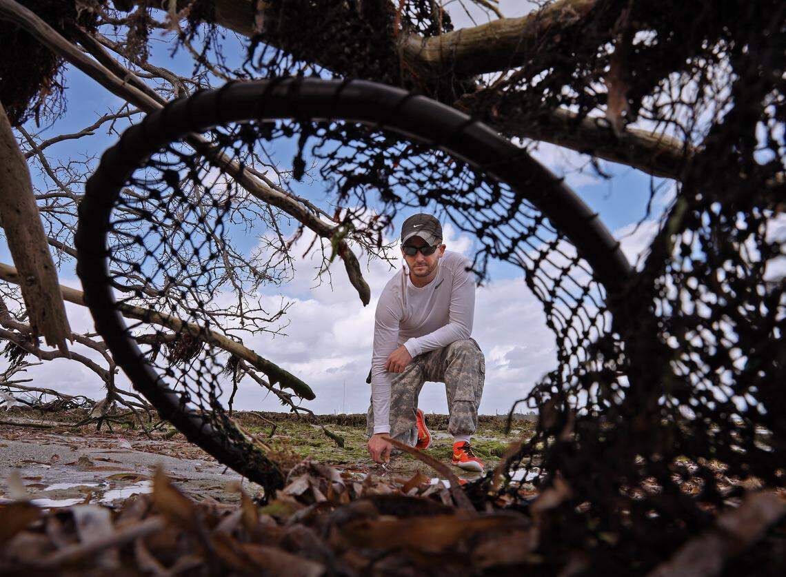 Andrew Otazo gets a closer look at discarded net and rope in the mangroves and coral reef at Bear Cut during low tide.