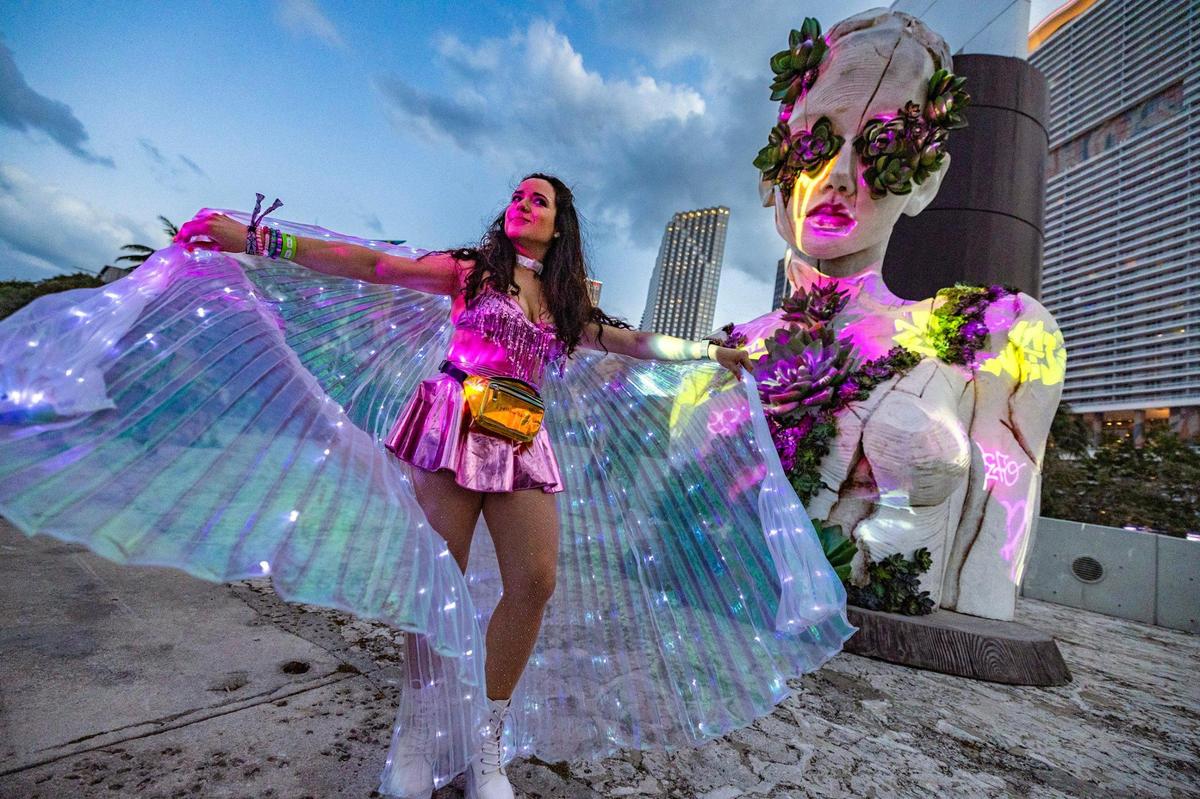 Penelope Regalado dances in front of a statue on display during Ultra Music Festival’s 25th anniversary at Bayfront Park, in Miami, Florida, on Friday, March 28, 2025.