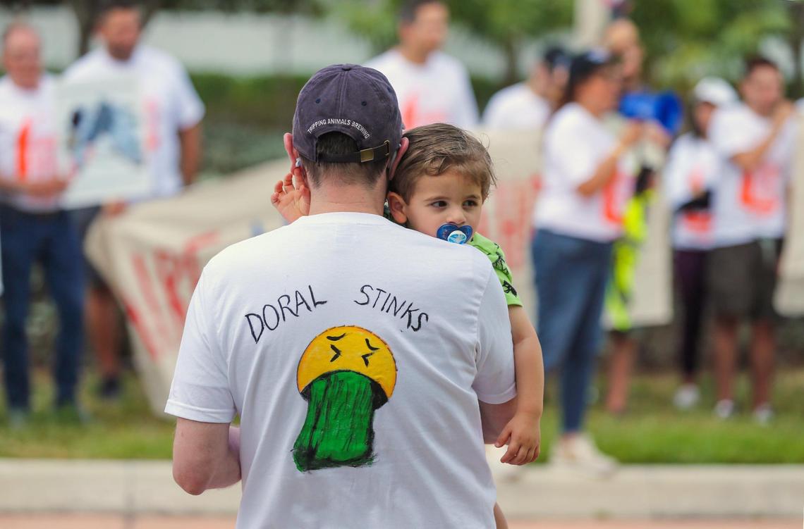 Manuel Rivas carries his son Mateo Rivas, 2, as Doral residents protest against a new garbage incinerator the county is considering in Doral on Saturday, April 23, 2022. The current incinerator is up for renewal.