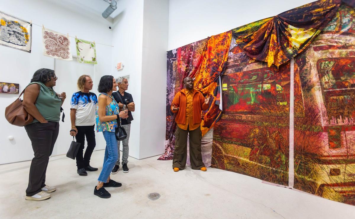 Cornelius Tulloch (center) explains his work to a crowd of guests before his solo show opening party at the Andrew Reed Gallery on Thursday, July 11, 2024 in Miami, Fla.