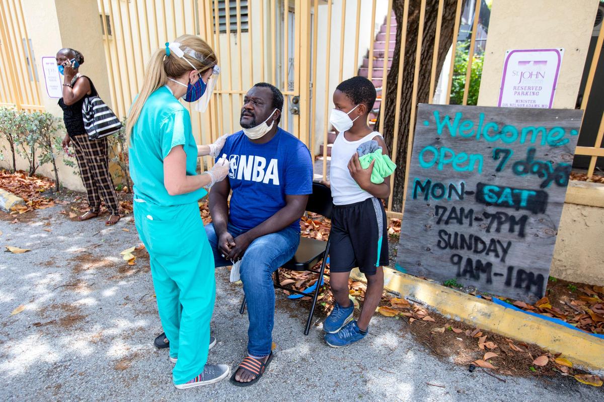 Stanley Kessling, 40, and Xavier Tyson, 9, wait to be tested fro the novel coronavirus during an extended services event for the unhoused, hosted by Dr. Armen Henderson, Dream Defenders and a coalition of community organizations and medical providers at St. John Institutional Missionary Baptist Church in Overtown, Florida on Friday, April 24, 2020.