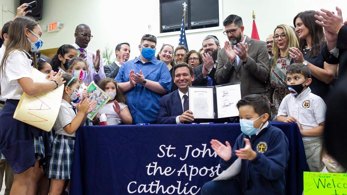 El gobernador Ron DeSantis (centro) celebrando después de firmar un proyecto de ley en St. John the Apostle Catholic School en Hialeah, Florida, el 11 de mayo de 2021. El proyecto de ley amplía y moderniza los programas de becas y cupones escolares del estado.